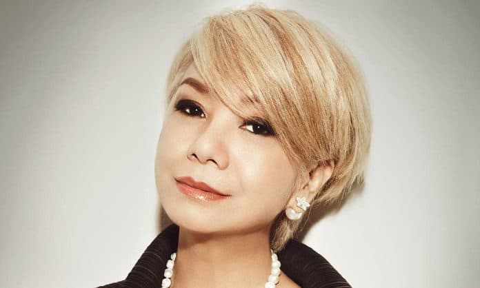 Closeup photo of Datin Dr. Winnie Loo in a black top with jewelry against a white gradient background