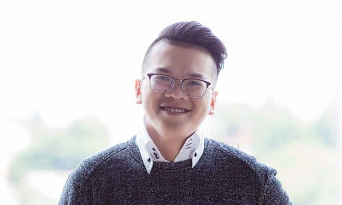 Bust portrait photo of Jaxon Ang in a collared shirt and sweater with a blurred background