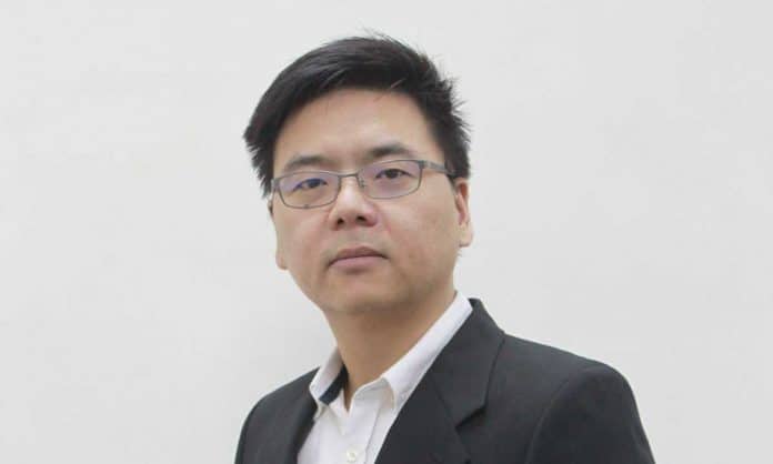 Bust portrait photo of Matthew Wong in a white dress shirt and black suit with a white background