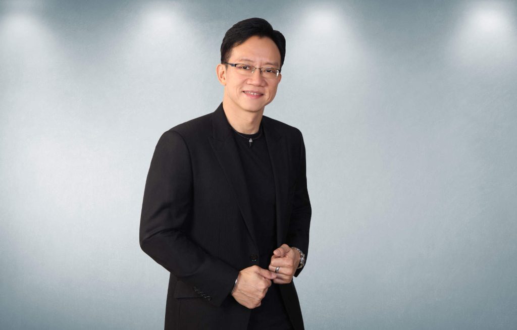 Half-body portrait photo of Ian Ong in a black suit with a white background