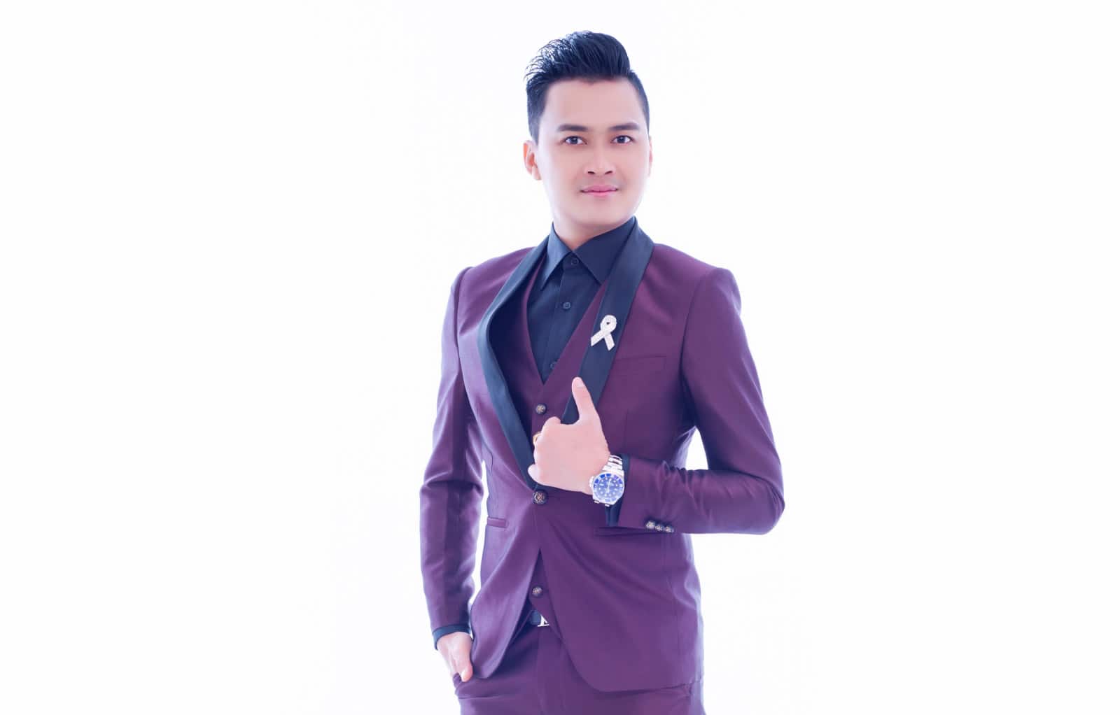Half-body portrait photo of Lim Sen Tian in a black dress shirt and plum suit, posing in front of a white background with one hand over lapels