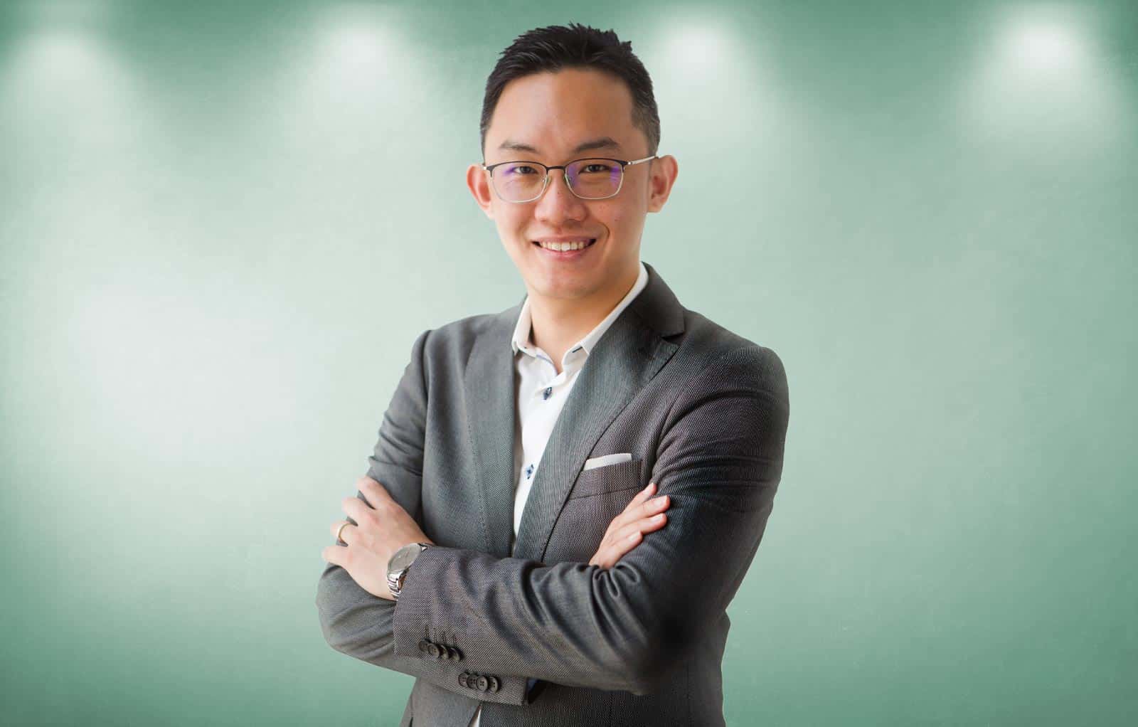 Half-body portrait photo of Yeouchiang Eng in a gray suit with a gray-green background